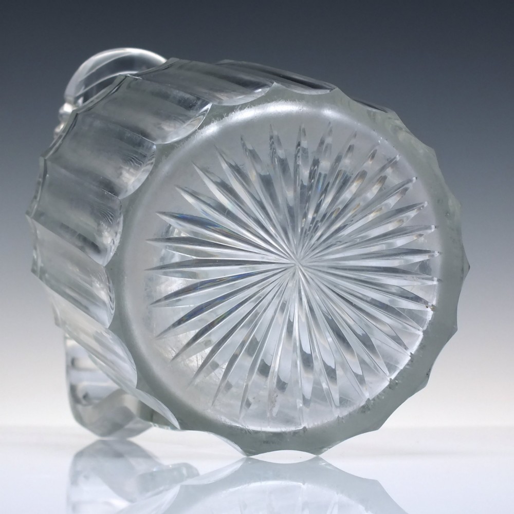 A clear Georgian Regency cut glass claret jug with a step-cut neck, panelled body, applied handle, and faceted stopper. View VI