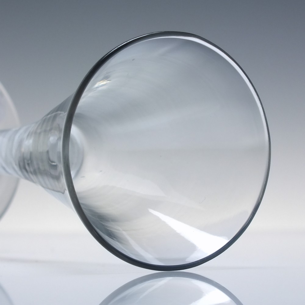 An 18th-century clear lead glass wine glass featuring a flared trumpet bowl, a central white opaque twist stem, and a circular conical foot. View V