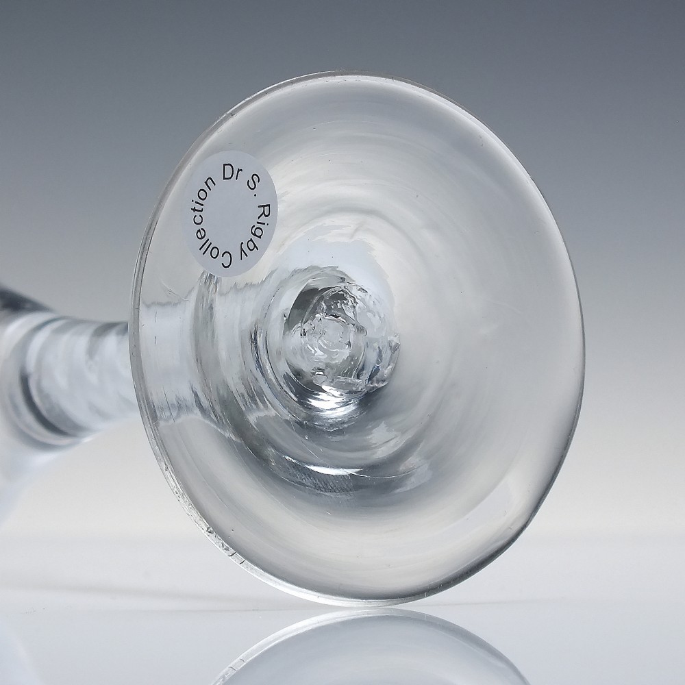An 18th-century clear lead glass wine glass featuring a flared trumpet bowl, a central white opaque twist stem, and a circular conical foot. View VI