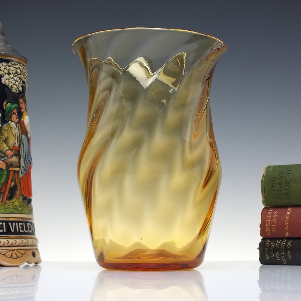 An amber crystal vase featuring a twisted optical swirl pattern and a flared rim.