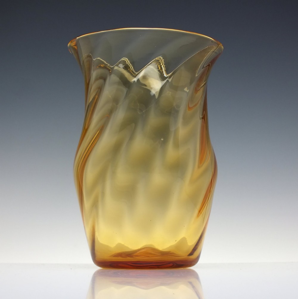 An amber crystal vase featuring a twisted optical swirl pattern and a flared rim. View II