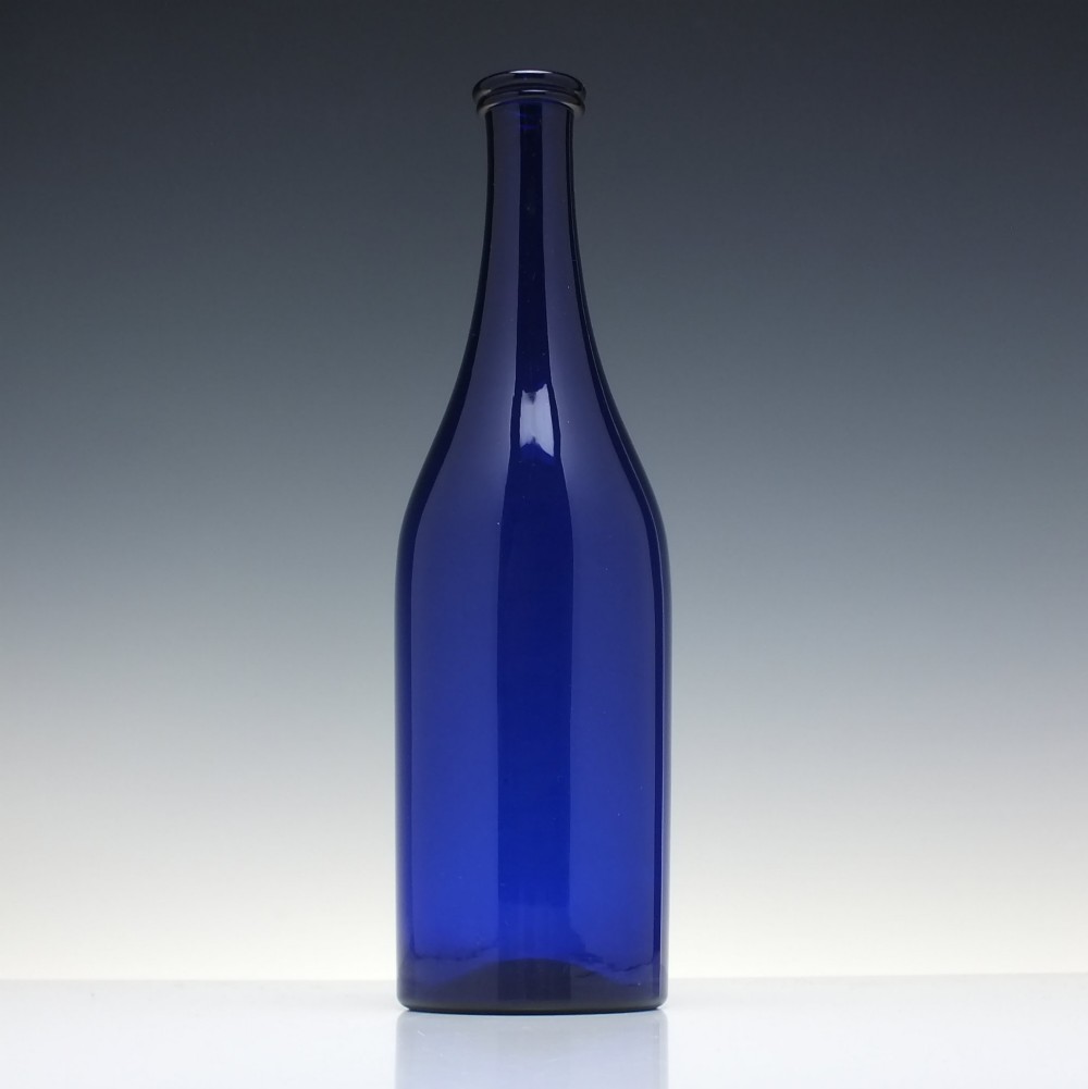 A dark cobalt blue Victorian hand-blown glass serving bottle featuring a tapered neck, double collar, and smooth cylindrical body. View III