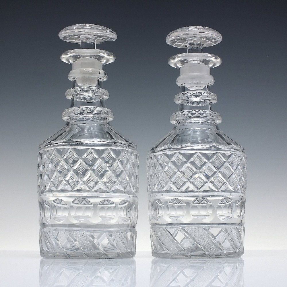 A pair of clear cut lead crystal Georgian decanters featuring diamond cut bands, neck rings, and mushroom stoppers. View II