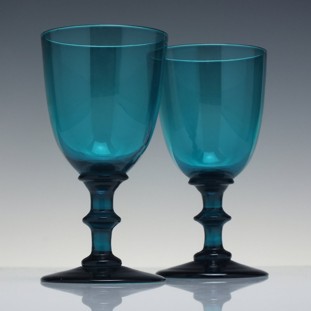 A pair of Georgian teal blue hand-blown glass wine goblets featuring knopped stems and circular bases.