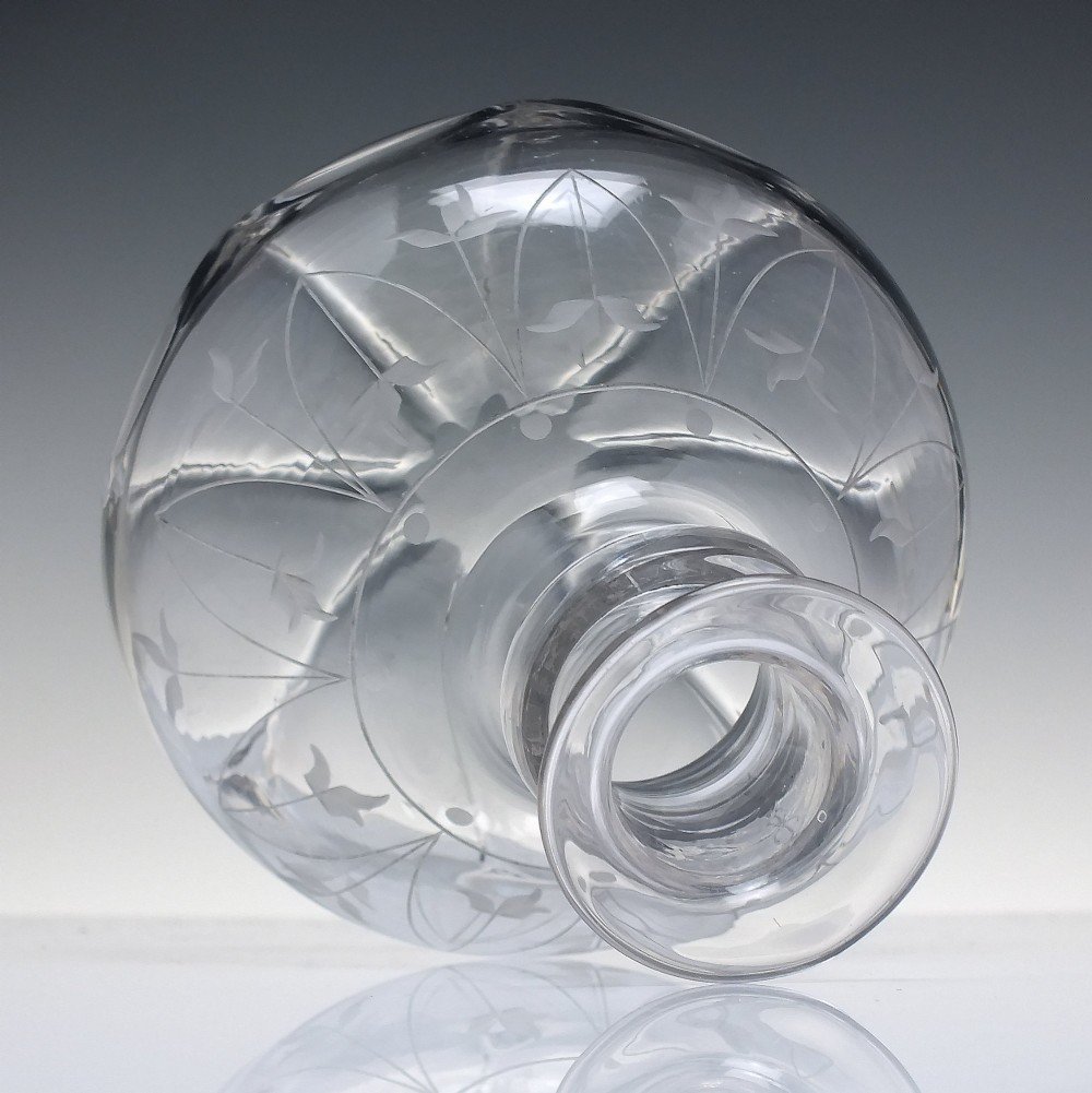 A mid-19th century clear glass wine carafe featuring an engraved foliate upper band and cut panel arches around the bulbous base. View II