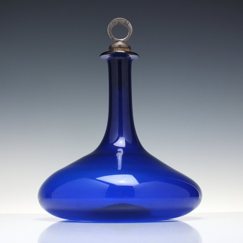 A Georgian cobalt blue glass mell decanter with a wide rounded base, narrow neck, and a cork stopper with a metal ring labeled RUM. View II