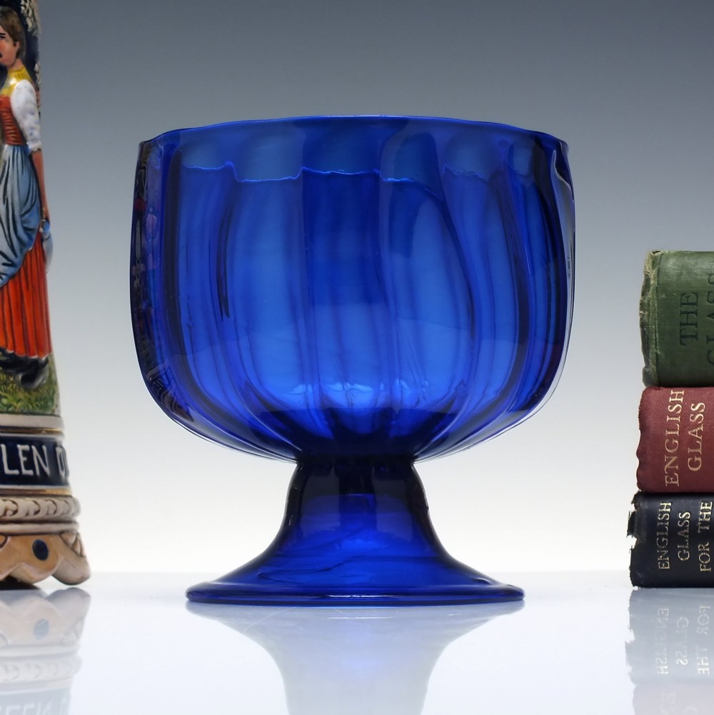 A deep cobalt blue glass sugar bowl featuring a vertically ribbed body set upon a conical pedestal foot.
