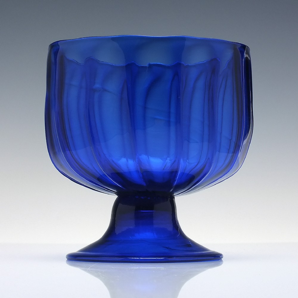 A deep cobalt blue glass sugar bowl featuring a vertically ribbed body set upon a conical pedestal foot. View II
