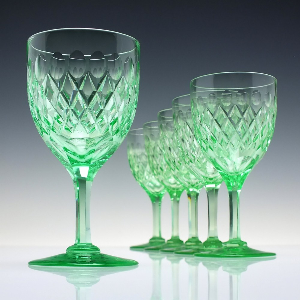 A set of six Victorian light green vaseline glass wine goblets featuring diamond-cut bowls and faceted stems.