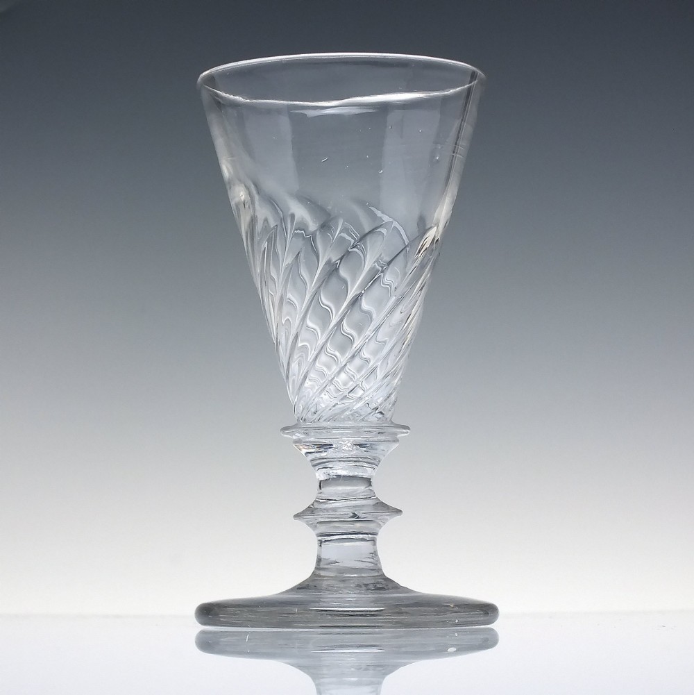 A clear Georgian lead glass ale goblet featuring half wrythen spiral moulding on the conical bowl and a knopped stem. View II