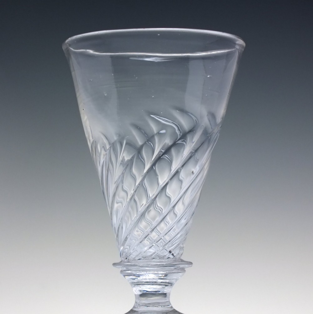A clear Georgian lead glass ale goblet featuring half wrythen spiral moulding on the conical bowl and a knopped stem. View IV