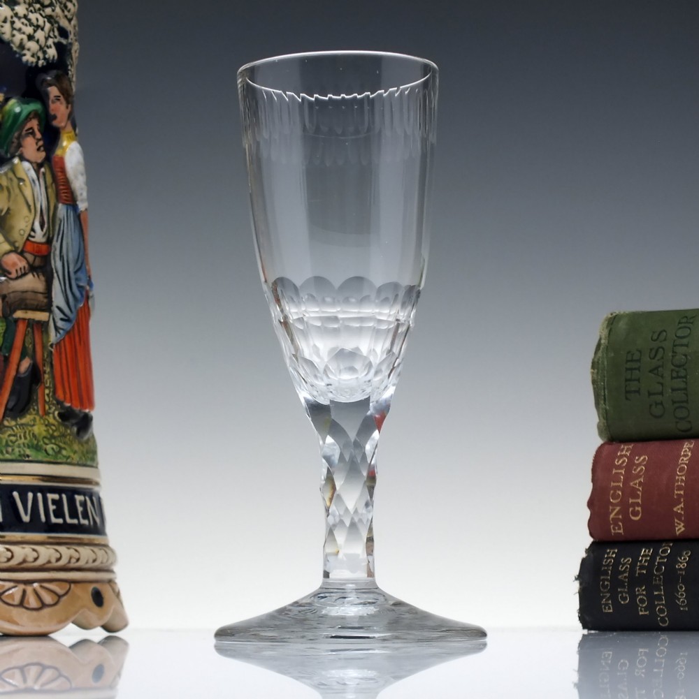 An 18th-century clear lead crystal ale glass featuring a faceted stem, a wide conical foot, and geometric cut decoration on the bowl.