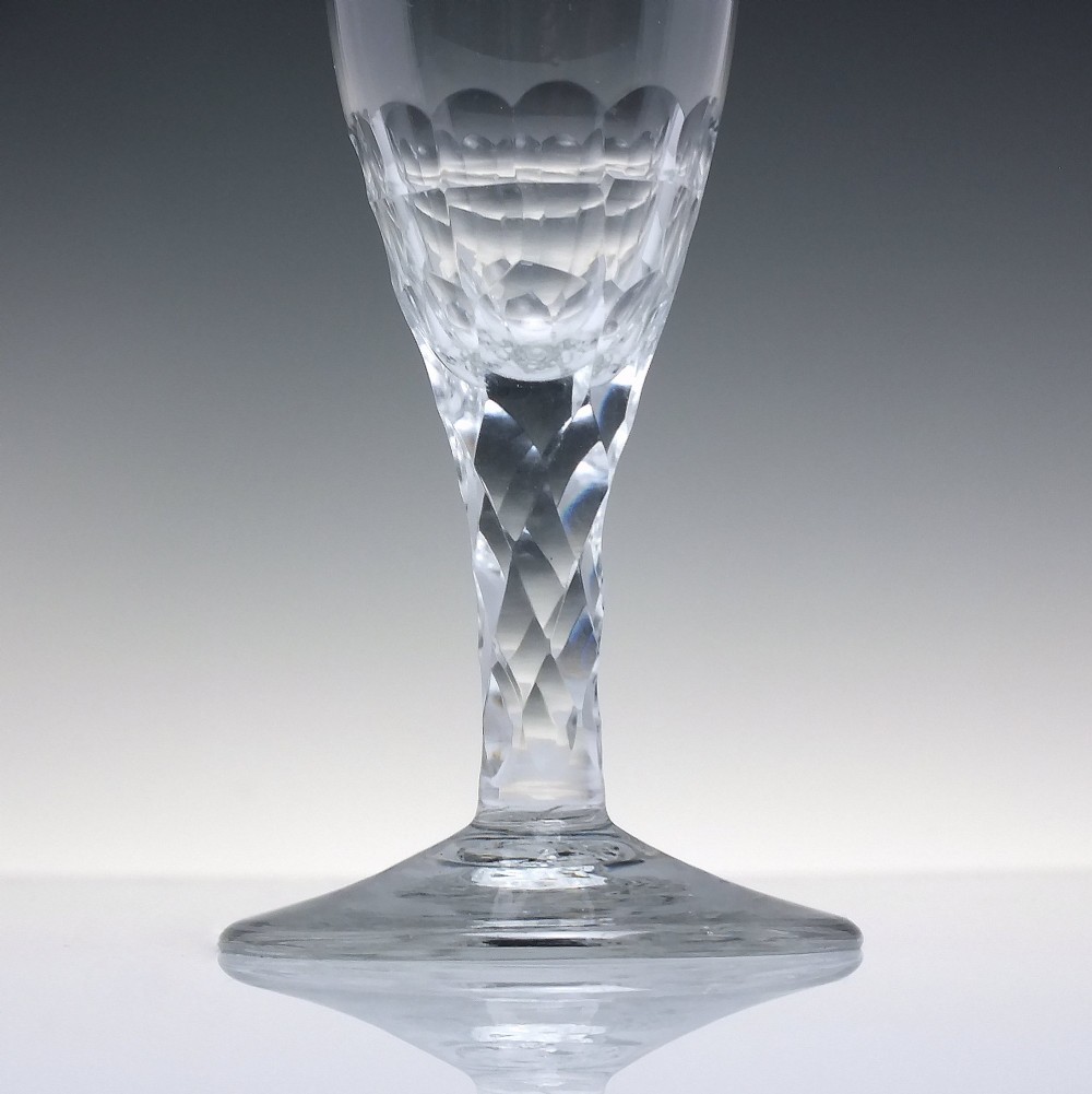 An 18th-century clear lead crystal ale glass featuring a faceted stem, a wide conical foot, and geometric cut decoration on the bowl. View III