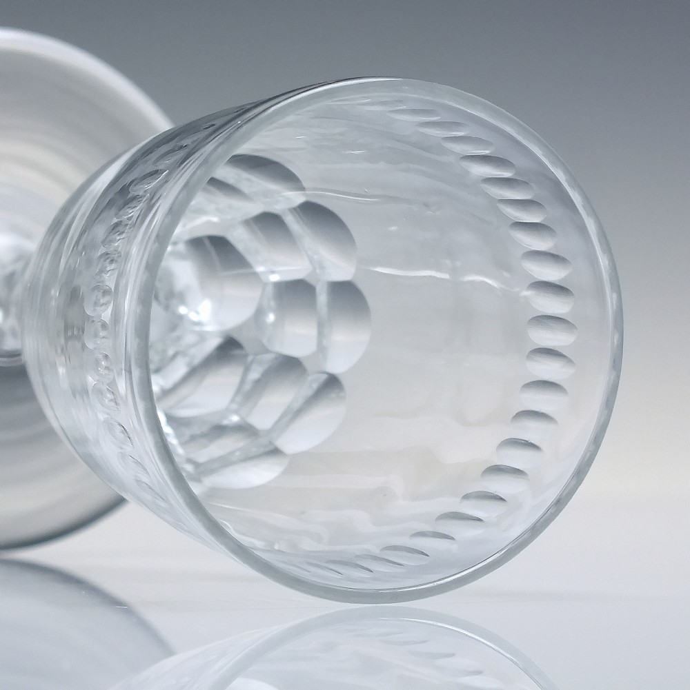 An 18th-century clear lead crystal ale glass featuring a faceted stem, a wide conical foot, and geometric cut decoration on the bowl. View V