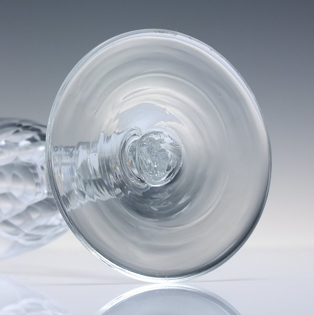 An 18th-century clear lead crystal ale glass featuring a faceted stem, a wide conical foot, and geometric cut decoration on the bowl. View VI