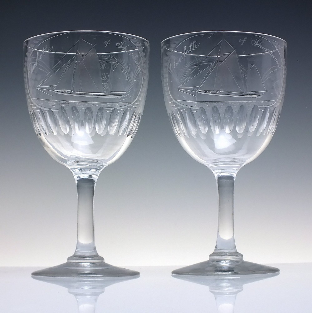 A pair of clear glass Victorian wine goblets featuring wheel-engraved sailing ships, inscriptions, and cut oval fluting around the lower bowls. View II