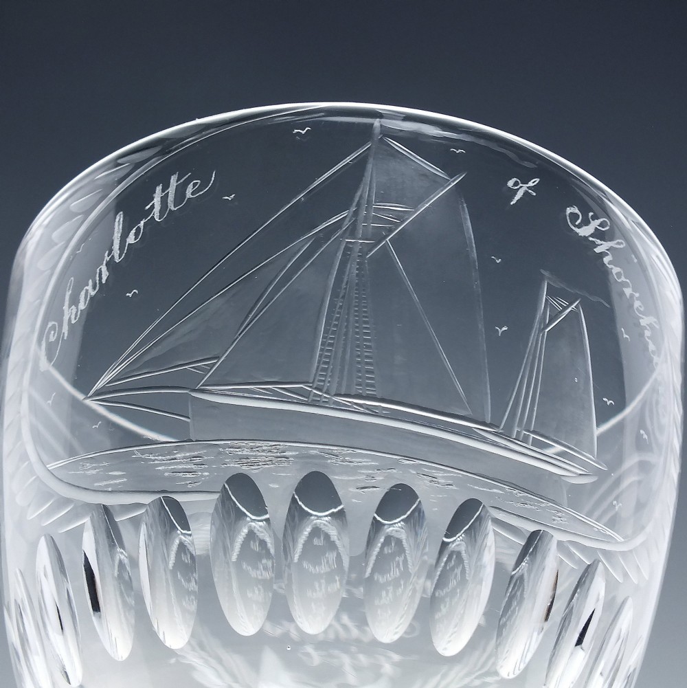 A pair of clear glass Victorian wine goblets featuring wheel-engraved sailing ships, inscriptions, and cut oval fluting around the lower bowls. View V