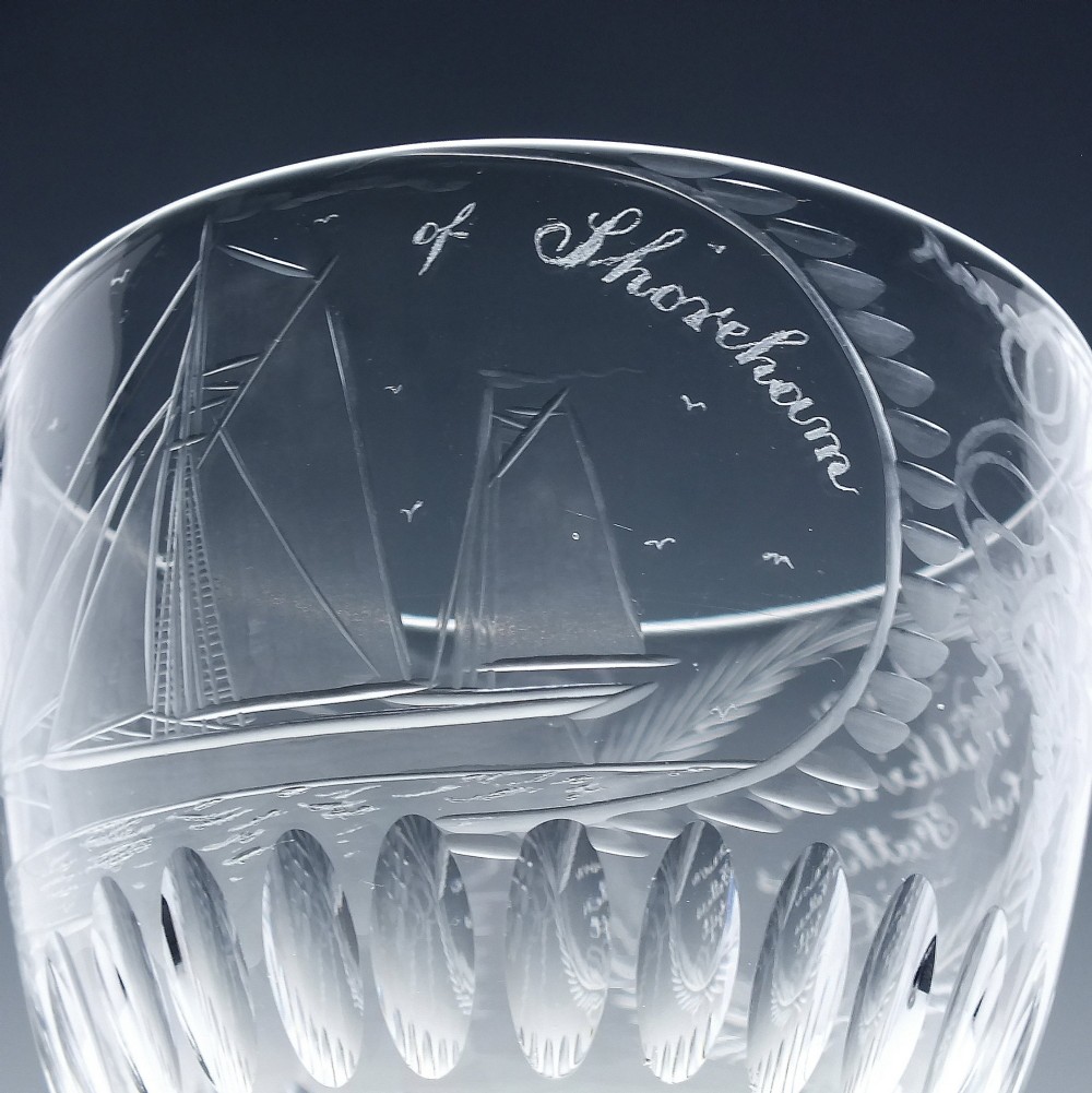 A pair of clear glass Victorian wine goblets featuring wheel-engraved sailing ships, inscriptions, and cut oval fluting around the lower bowls. View VII