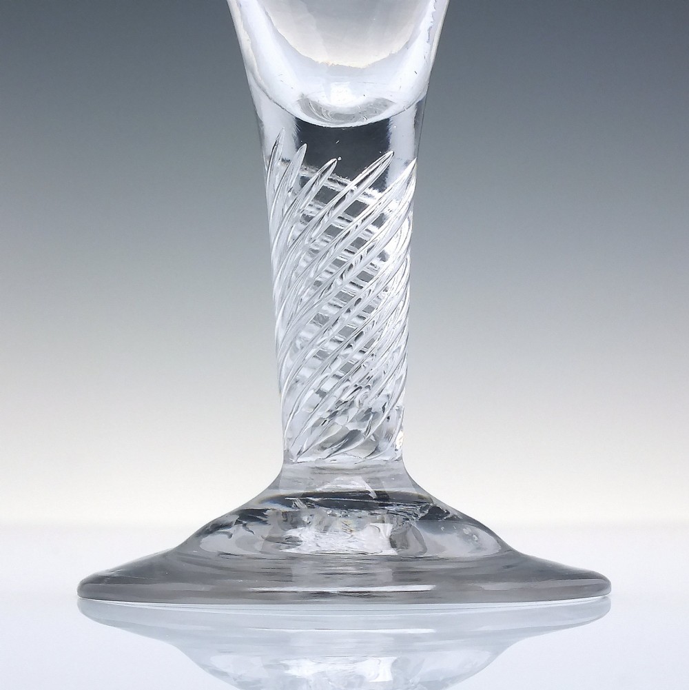 A clear Georgian dram glass featuring a flared trumpet bowl, a multi-spiral air twist stem, and a broad conical foot. View III