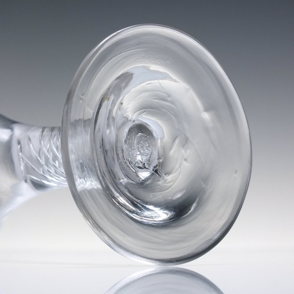 A clear Georgian dram glass featuring a flared trumpet bowl, a multi-spiral air twist stem, and a broad conical foot. View VI