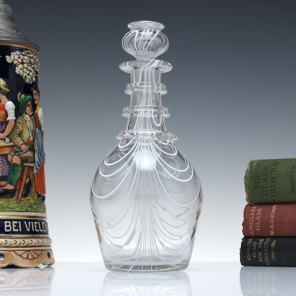 A clear lead glass Regency Prussian-shaped personal spirit decanter decorated with combed opaque white trailing and fitted with a matching glass stopper.