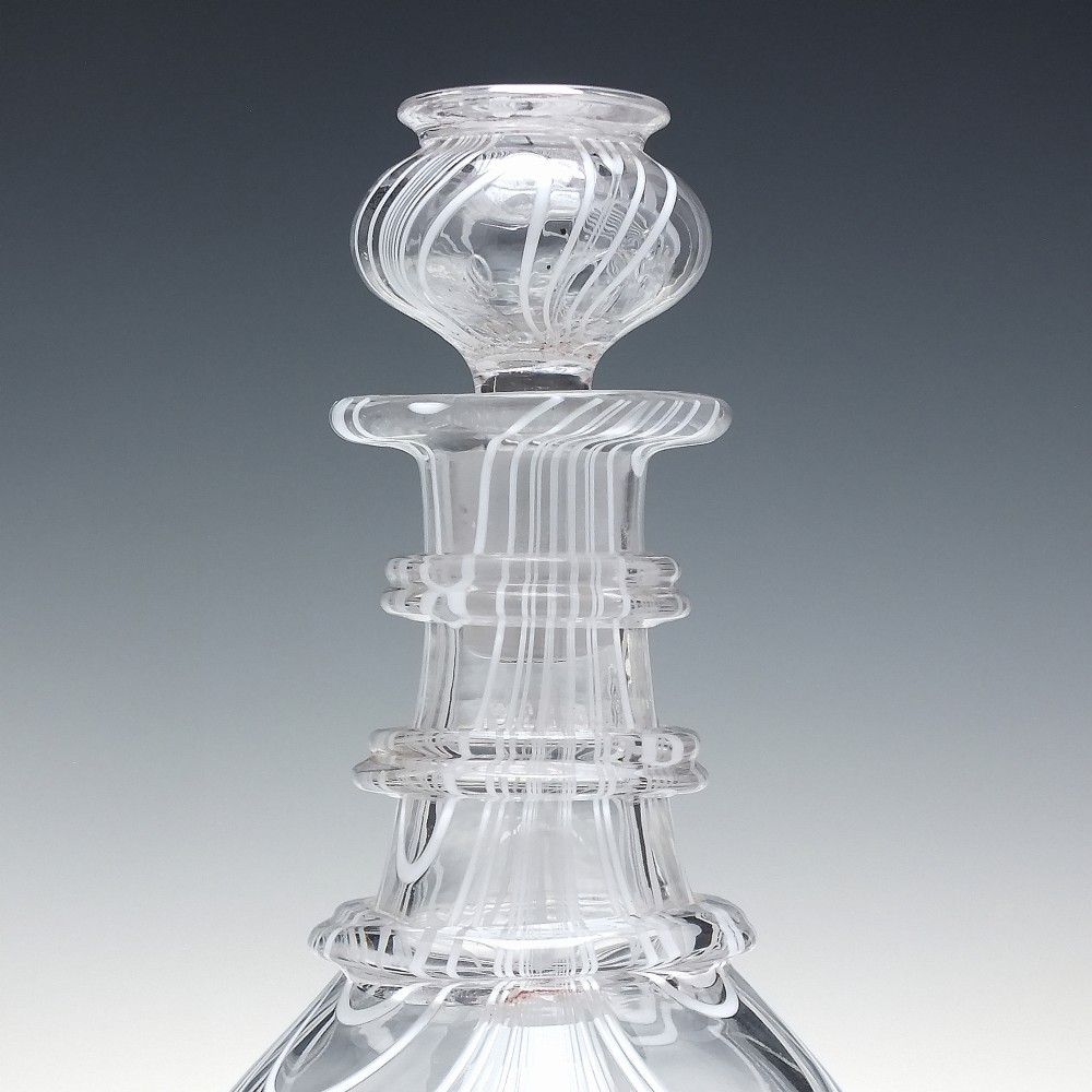 A clear lead glass Regency Prussian-shaped personal spirit decanter decorated with combed opaque white trailing and fitted with a matching glass stopper. View V