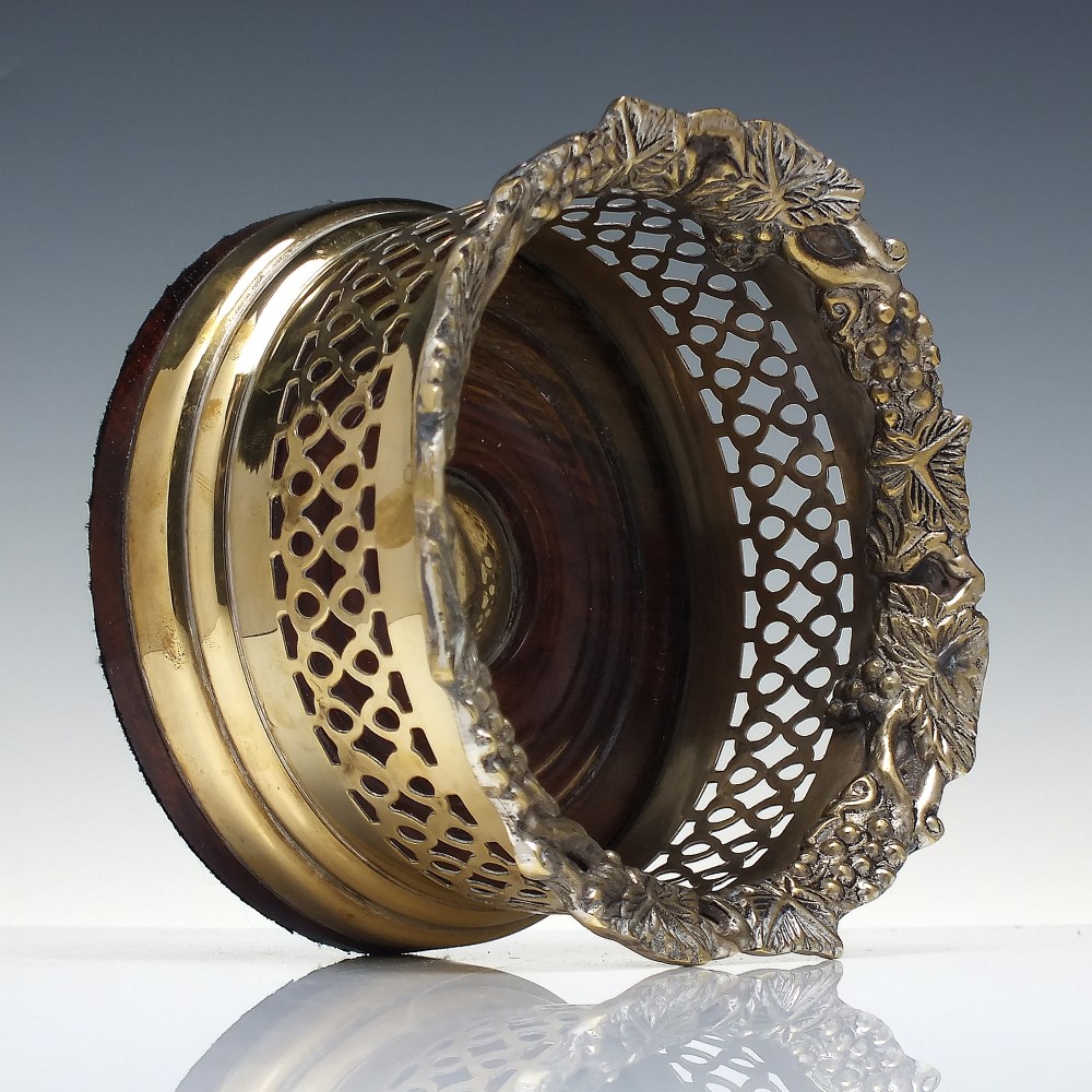 A Victorian gilded and silver plate champagne bottle coaster featuring a pierced lattice gallery, flared rim, and dark wood base. View III