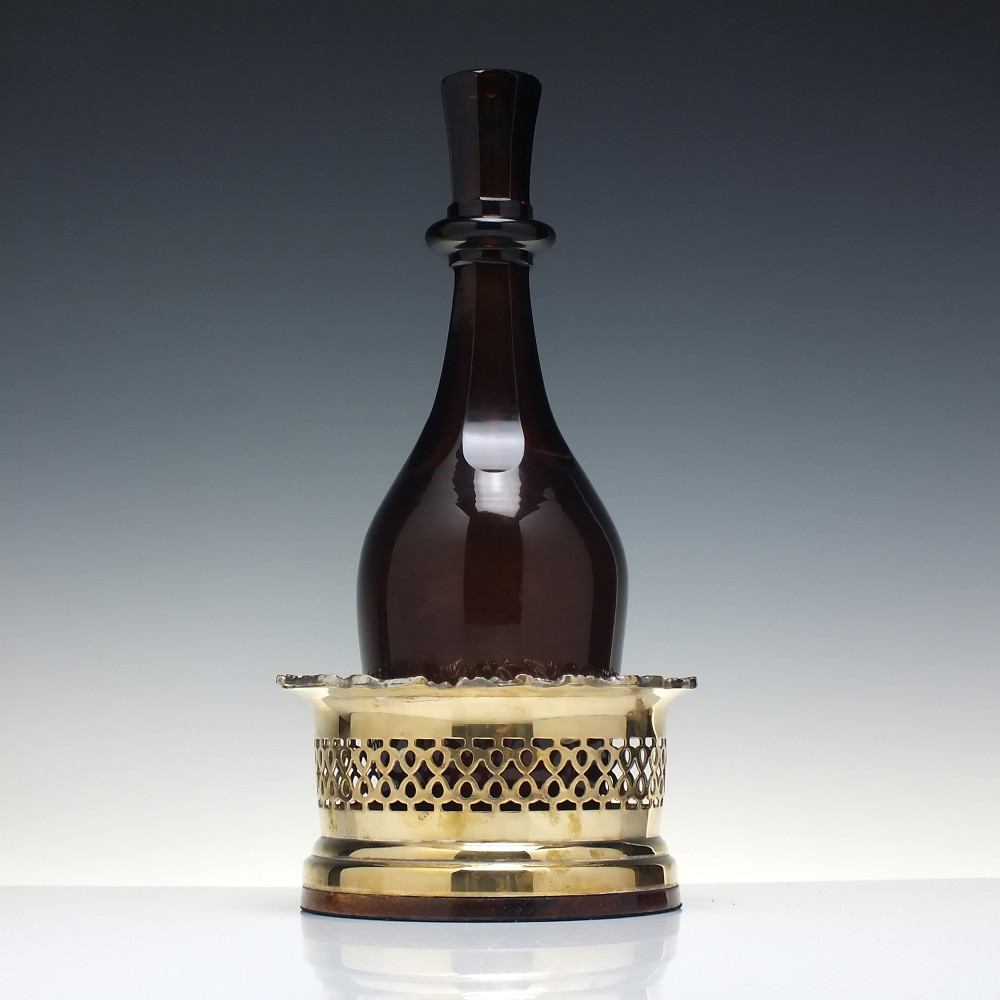 A Victorian gilded and silver plate champagne bottle coaster featuring a pierced lattice gallery, flared rim, and dark wood base. View VI