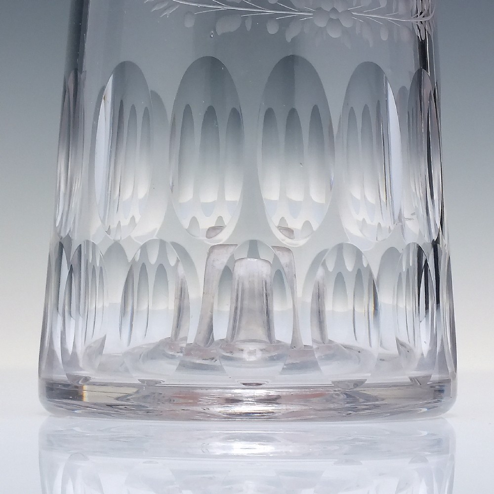 An 18th-century clear glass sugar loaf bitters bottle featuring a faceted slender neck, cut panel base, and wheel-engraved lettering spelling BITTERS surrounded by floral swags. View V