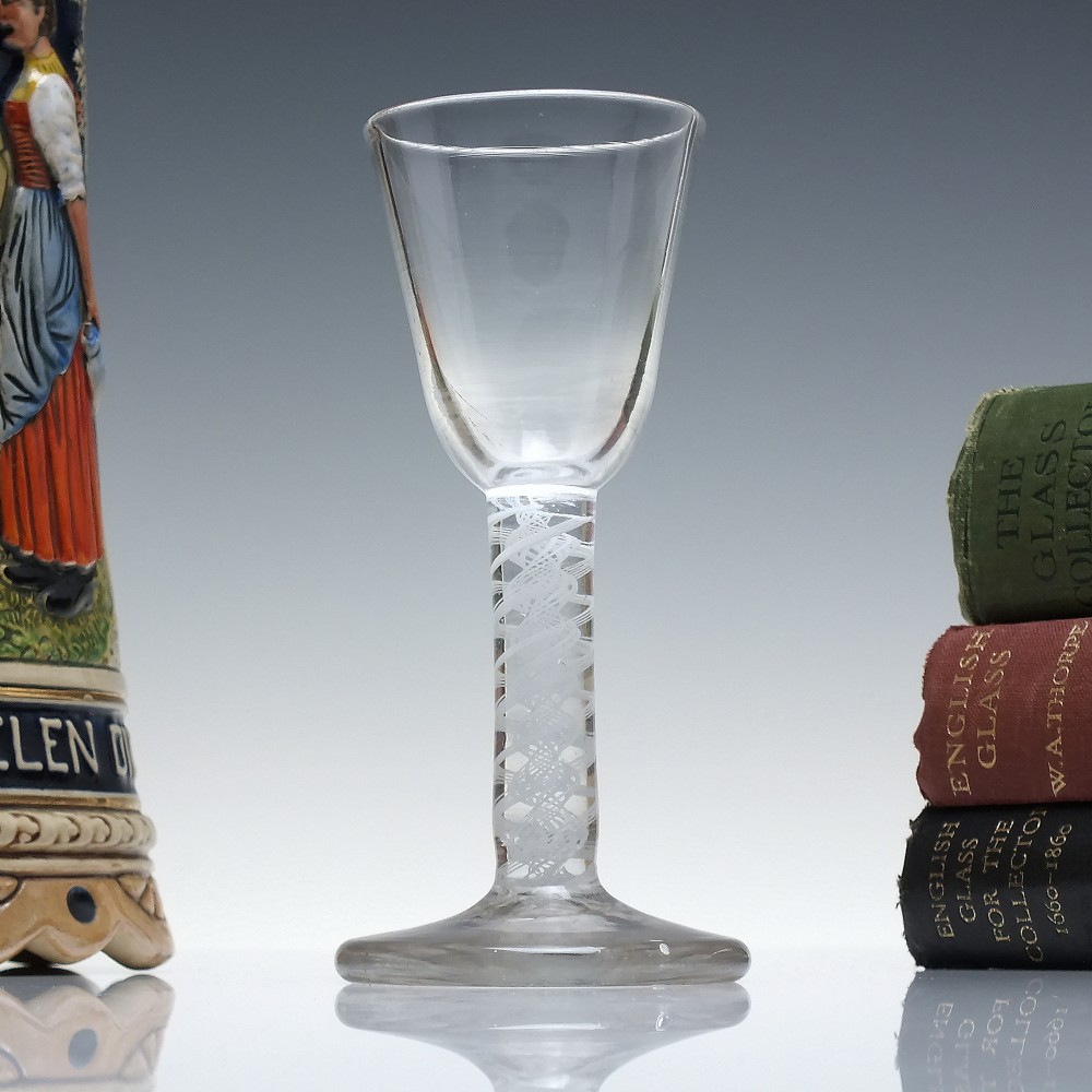 An 18th-century clear glass wine glass featuring an internal white opaque twist stem and a thickened firing foot base.