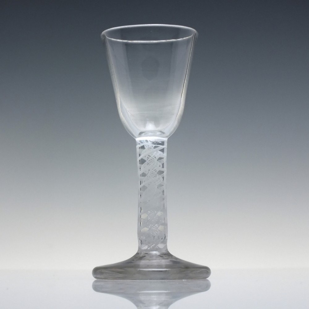 An 18th-century clear glass wine glass featuring an internal white opaque twist stem and a thickened firing foot base. View II