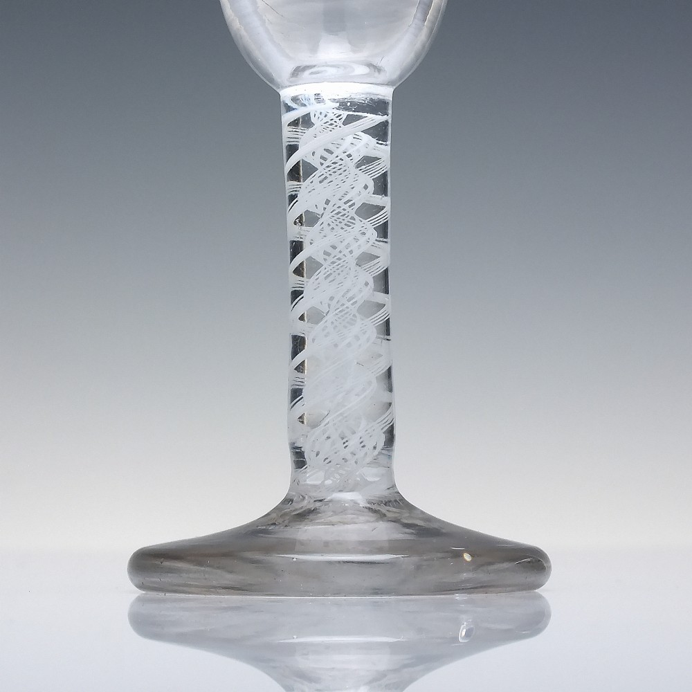 An 18th-century clear glass wine glass featuring an internal white opaque twist stem and a thickened firing foot base. View III
