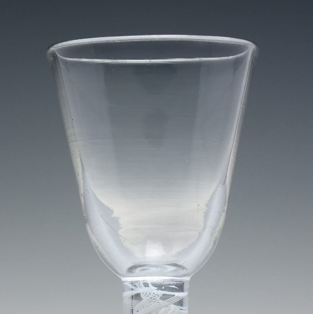 An 18th-century clear glass wine glass featuring an internal white opaque twist stem and a thickened firing foot base. View IV