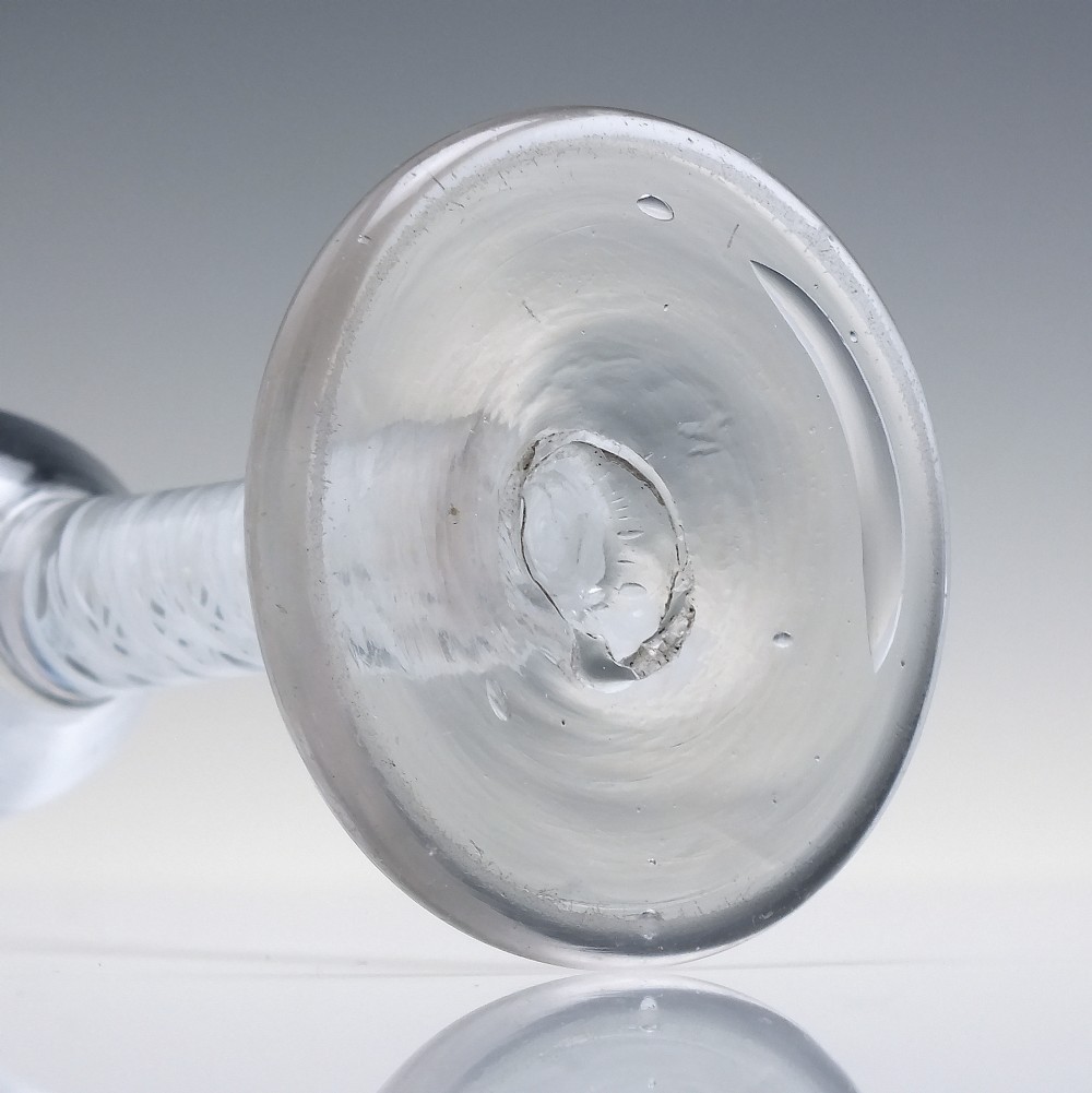 An 18th-century clear glass wine glass featuring an internal white opaque twist stem and a thickened firing foot base. View VI