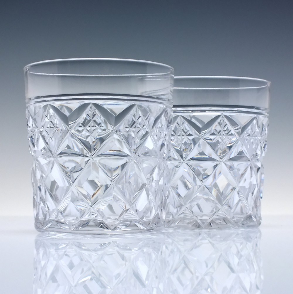 A pair of clear cut-crystal whisky tumblers featuring a deep diamond geometric pattern and smooth polished rims.