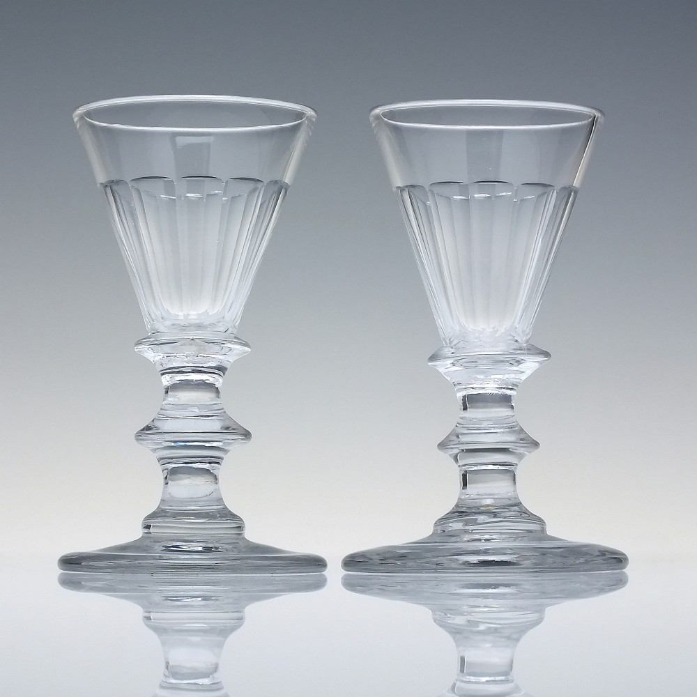 A pair of clear cut-glass Georgian dram glasses featuring conical bowls with vertical flutes and knopped stems on circular footed bases. View II