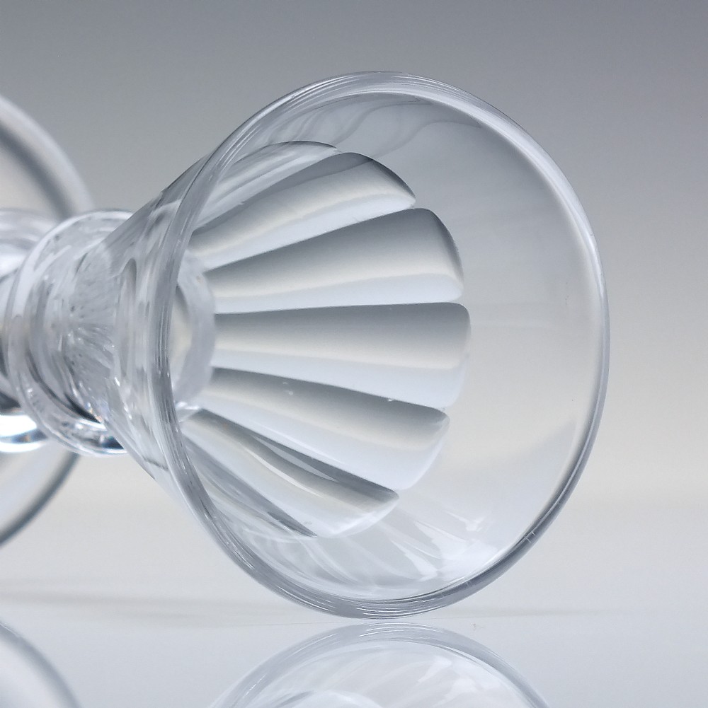 A pair of clear cut-glass Georgian dram glasses featuring conical bowls with vertical flutes and knopped stems on circular footed bases. View IV