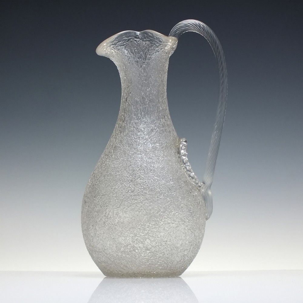 A late 19th-century Victorian clear overshot glass champagne jug with a textured ice-glass surface, flared spout, and an applied ribbed clear handle.