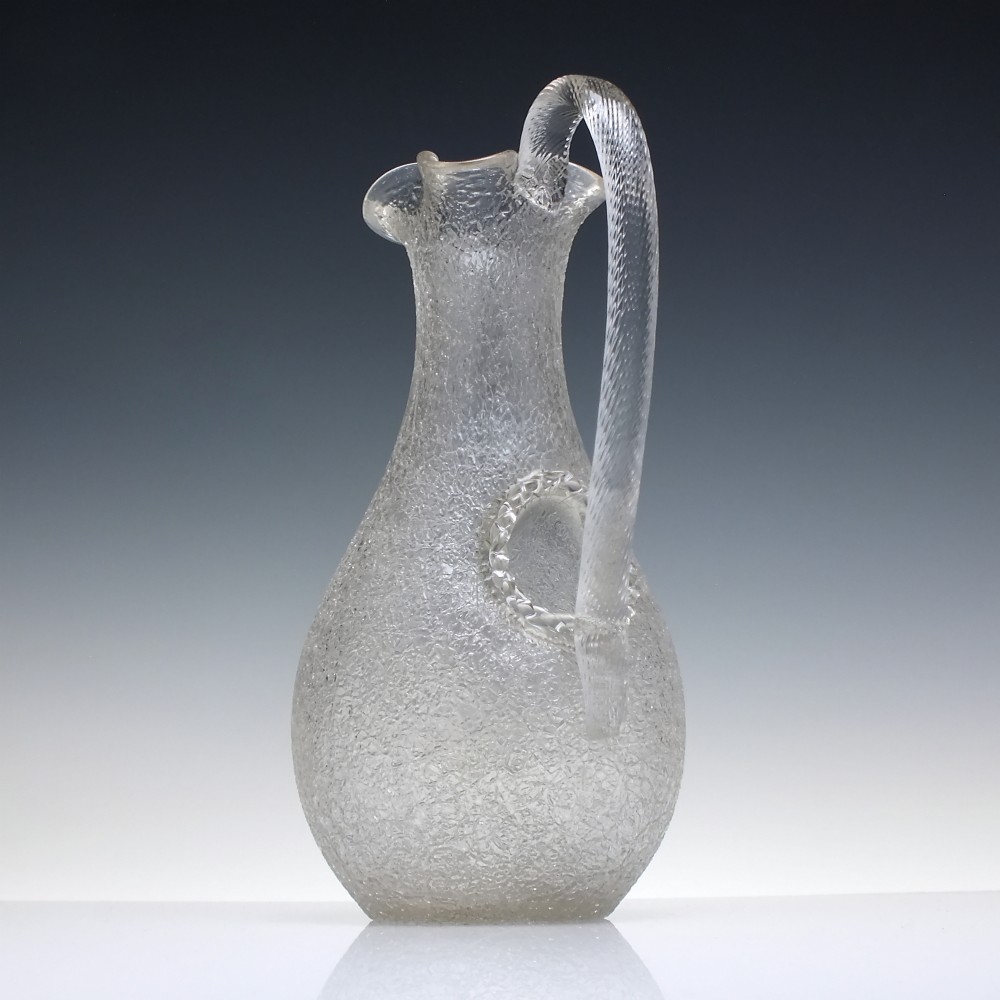 A late 19th-century Victorian clear overshot glass champagne jug with a textured ice-glass surface, flared spout, and an applied ribbed clear handle. View II