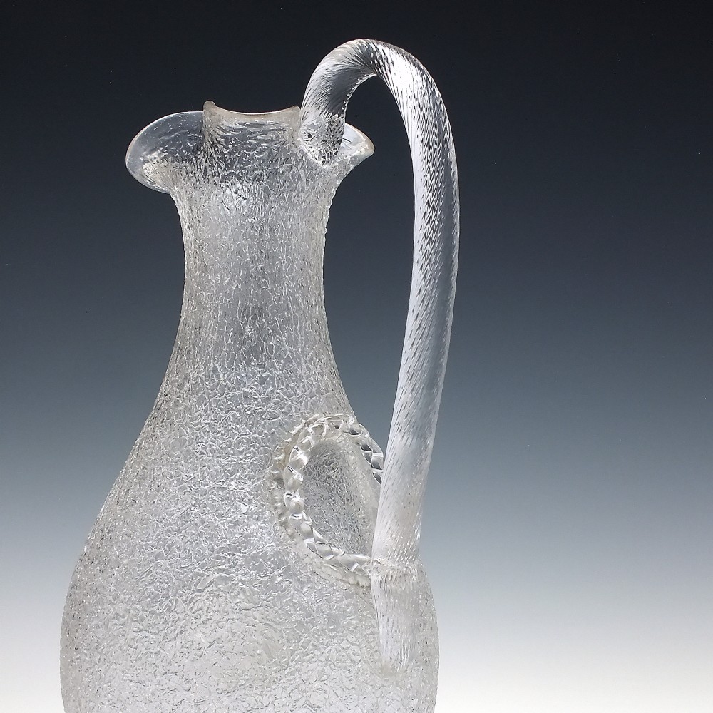 A late 19th-century Victorian clear overshot glass champagne jug with a textured ice-glass surface, flared spout, and an applied ribbed clear handle. View V