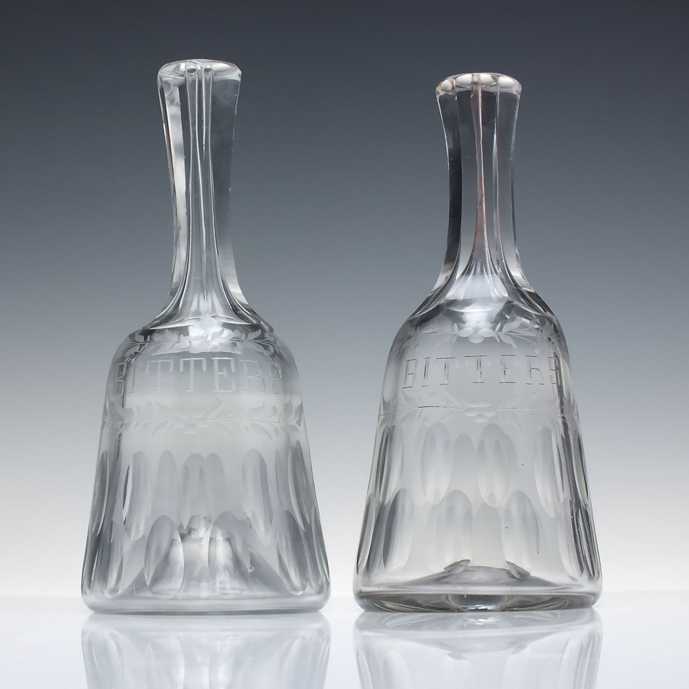 A pair of 18th-century clear glass sugar loaf bitters bottles featuring facet-cut long necks, hand-engraved floral garlands, and the word BITTERS cut into the body. View II
