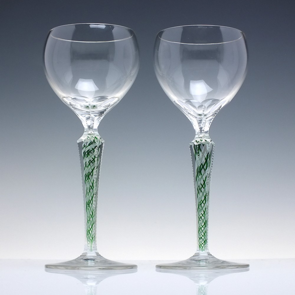A pair of clear glass wine goblets featuring round bowls and tall stems decorated with internal green and white opaque twists. View II