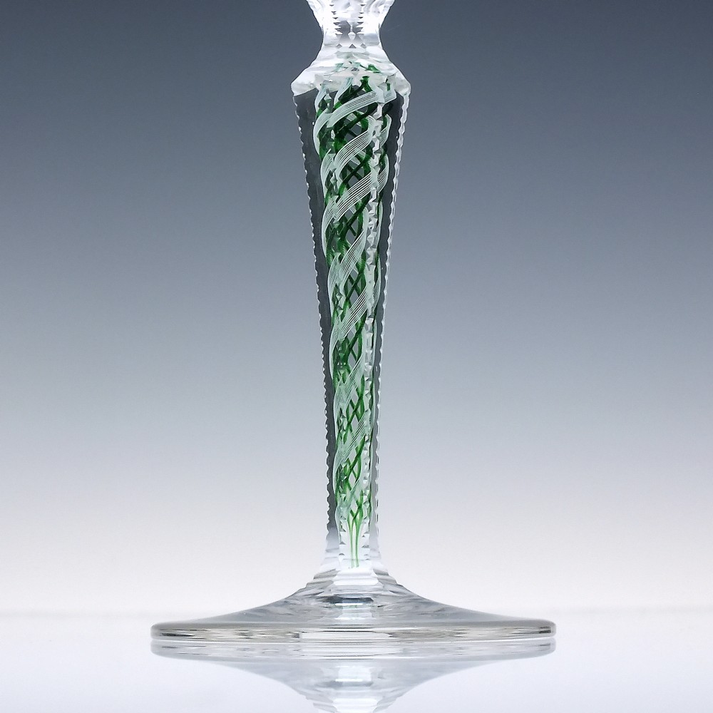 A pair of clear glass wine goblets featuring round bowls and tall stems decorated with internal green and white opaque twists. View IV