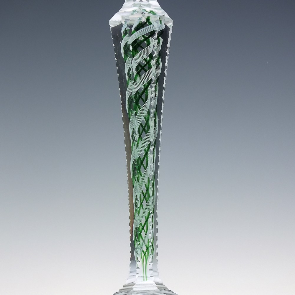 A pair of clear glass wine goblets featuring round bowls and tall stems decorated with internal green and white opaque twists. View V