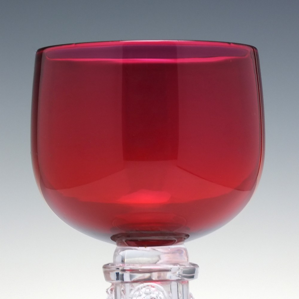 A pair of nineteenth-century Victorian wine glasses featuring deep cranberry red bowls and clear glass stems decorated with applied raspberry prunts. View IV