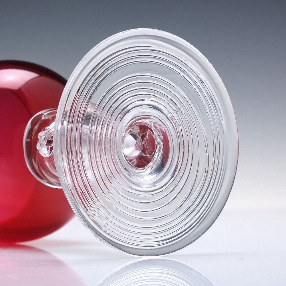 A pair of nineteenth-century Victorian wine glasses featuring deep cranberry red bowls and clear glass stems decorated with applied raspberry prunts. View VI