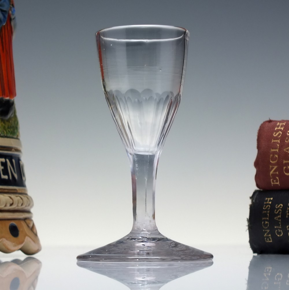 An 18th-century clear glass tincture glass featuring a fluted lower bowl, slender stem, and wide conical foot.