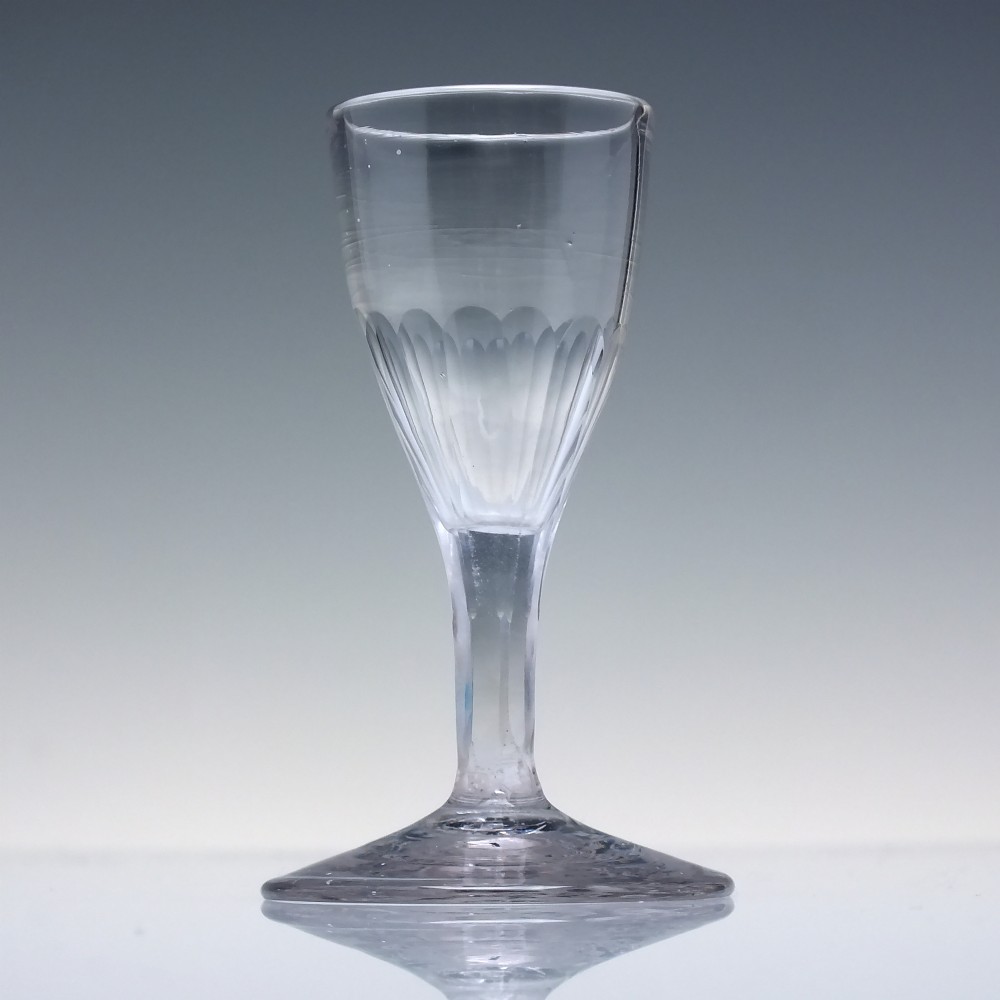 An 18th-century clear glass tincture glass featuring a fluted lower bowl, slender stem, and wide conical foot. View II