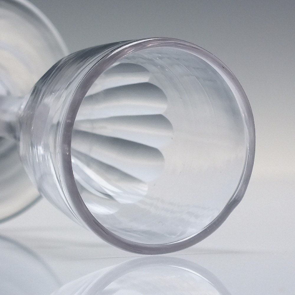 An 18th-century clear glass tincture glass featuring a fluted lower bowl, slender stem, and wide conical foot. View IV