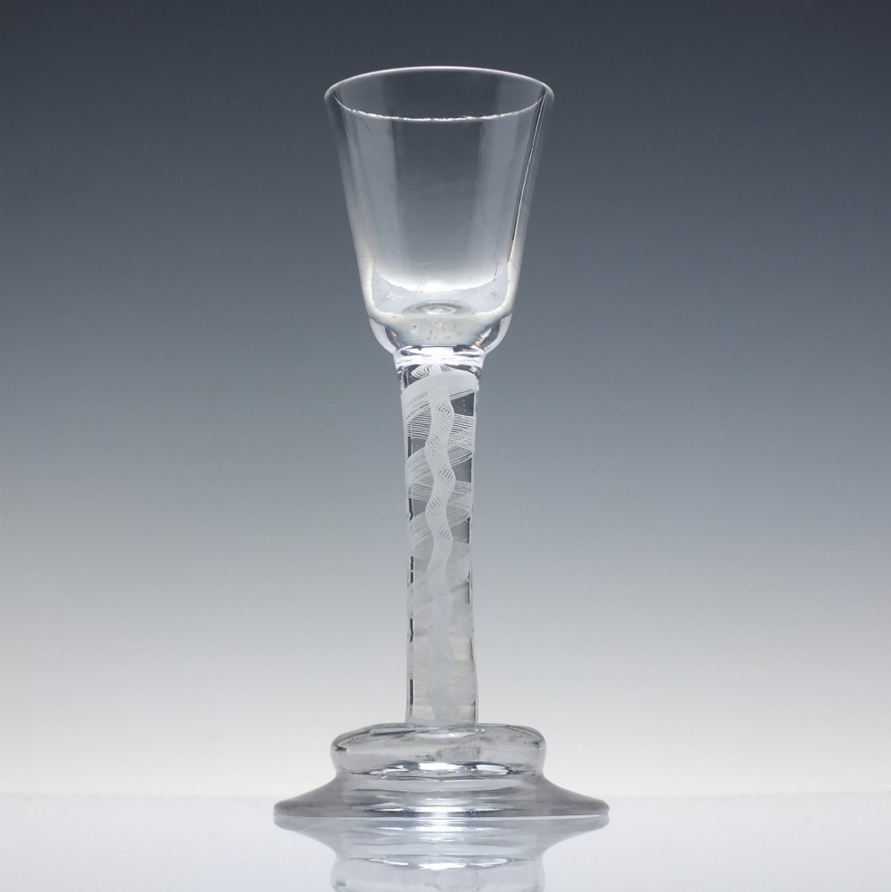 A clear Georgian lead glass wine glass featuring an internal white opaque twist stem and a stepped helmet foot. View II
